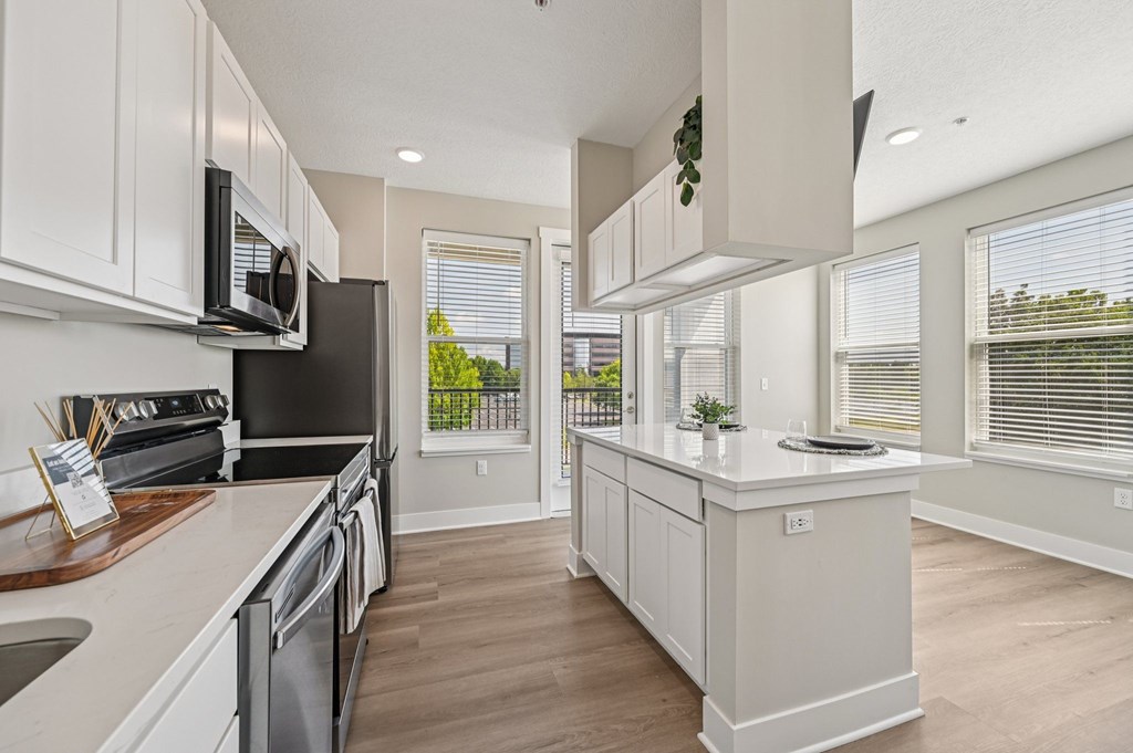 A modern kitchen with white cabinets and a black refrigerator.