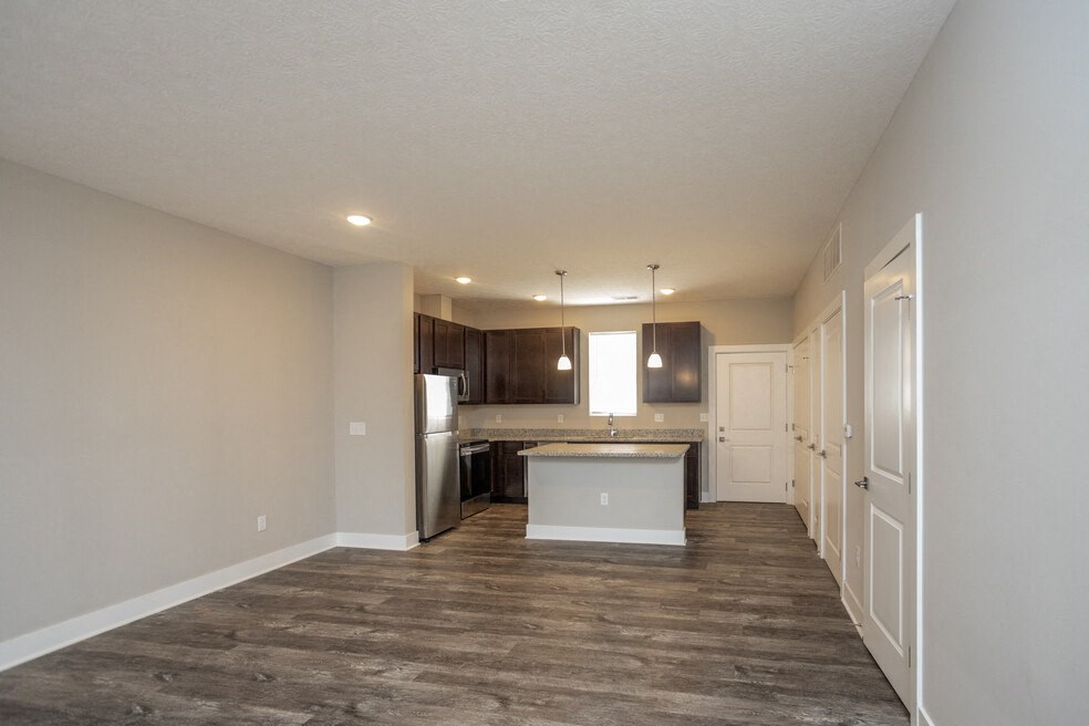 an empty living room and kitchen with a refrigerator and a sink