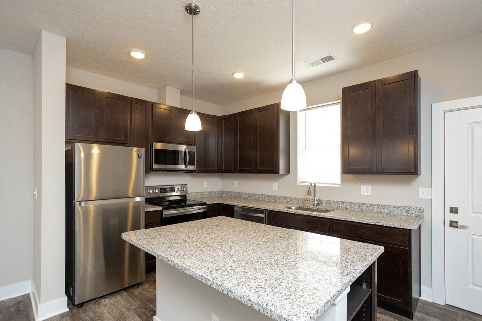 a kitchen with a marble counter top and stainless steel refrigerator