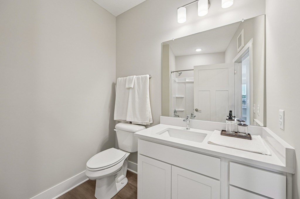 A white bathroom with a toilet, sink, and mirror.