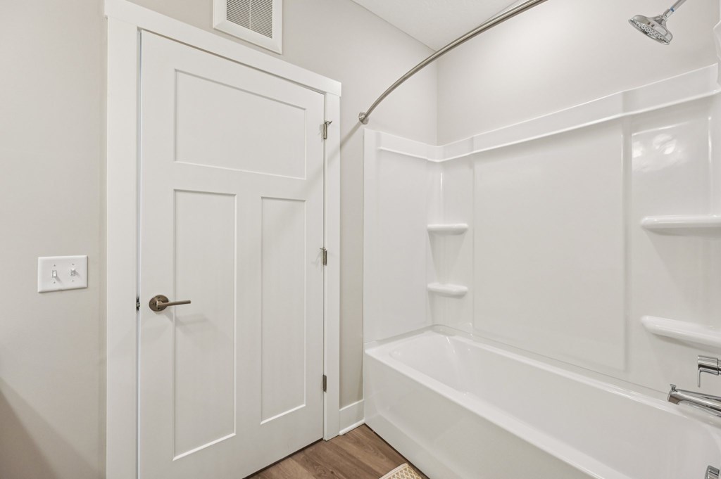A white bathroom with a door and a bathtub.
