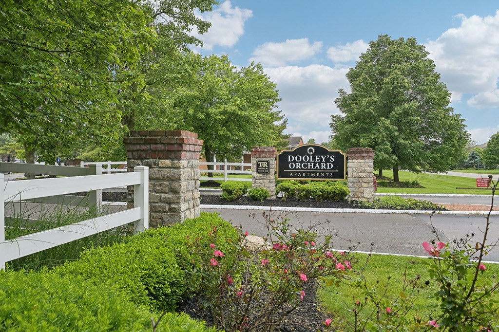 A sign for Dooley's Country Club is displayed in front of a white fence.