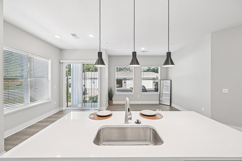 A modern kitchen with a large sink and pendant lights.
