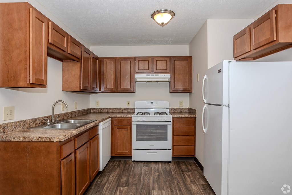 A kitchen with brown cabinets and white appliances.