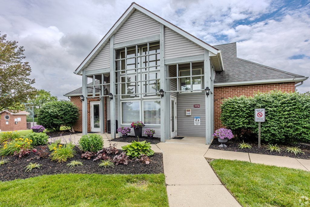 A building with a grey facade and a grey roof with a glass door and windows.