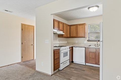 A kitchen with white appliances and wooden cabinets.