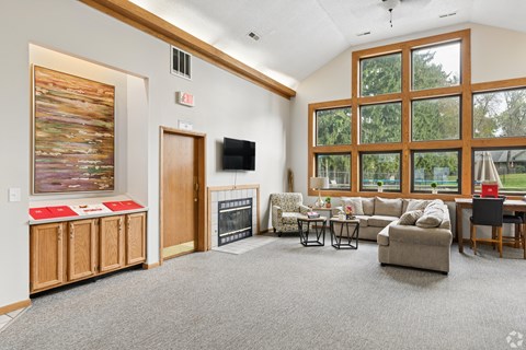 A living room with a grey carpet and a fireplace.