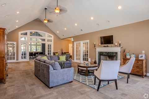 A living room with a grey couch, a white chair, a fireplace, and a television.