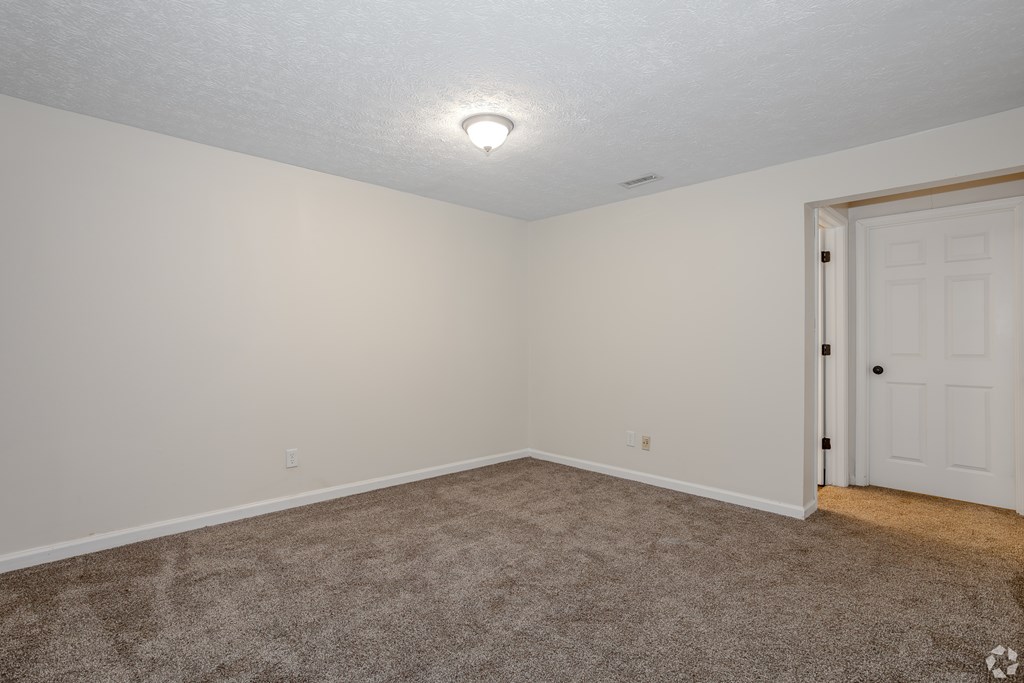 A room with a carpeted floor and a white door.