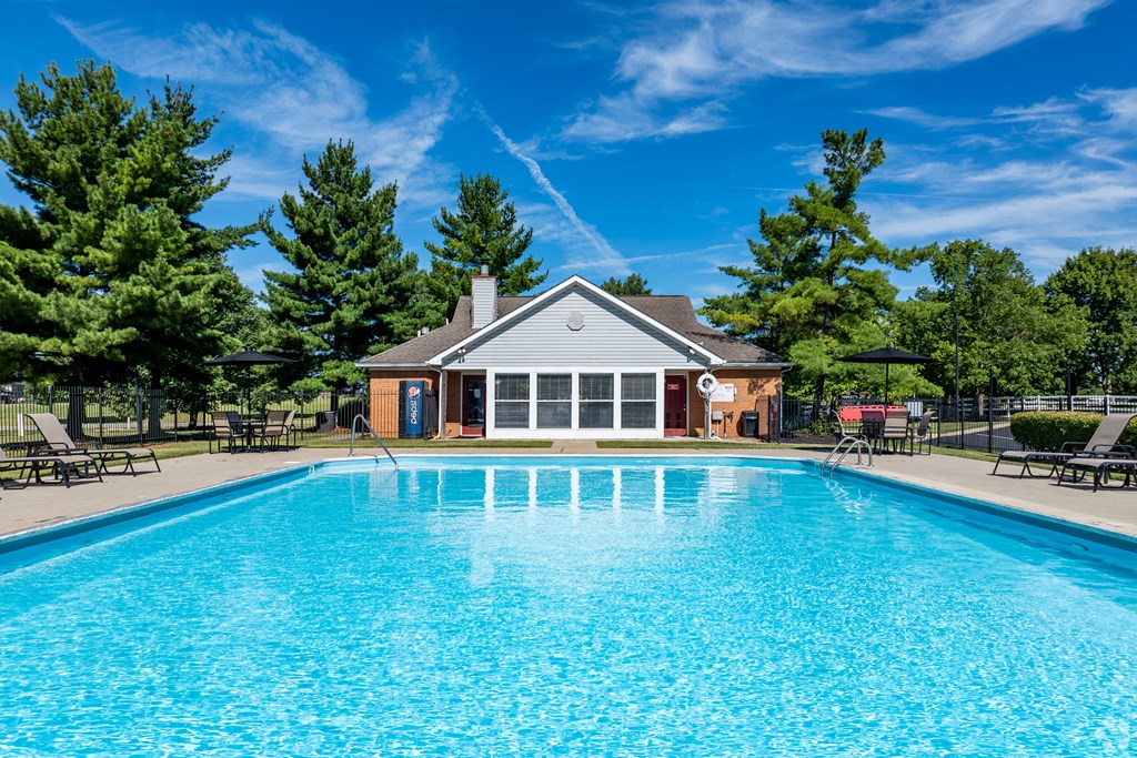A large swimming pool in front of a building surrounded by trees.