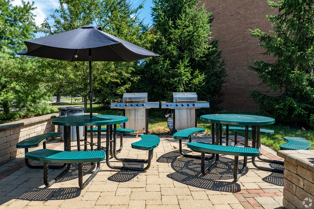 A patio with tables and chairs and a blue umbrella.