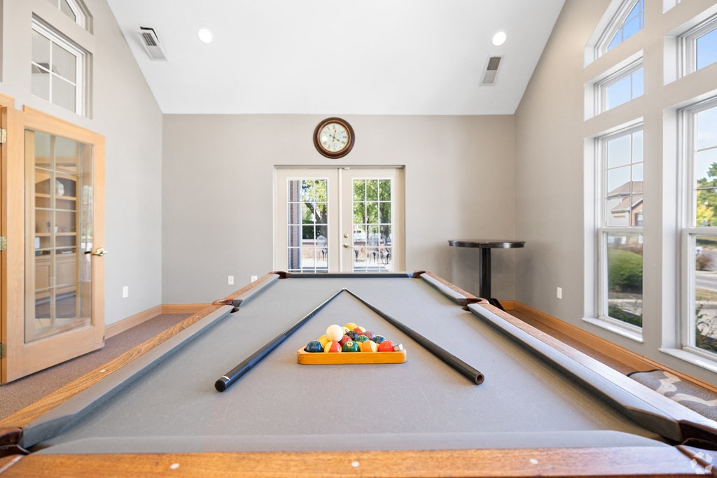 a billiards room with a pool table and a clock