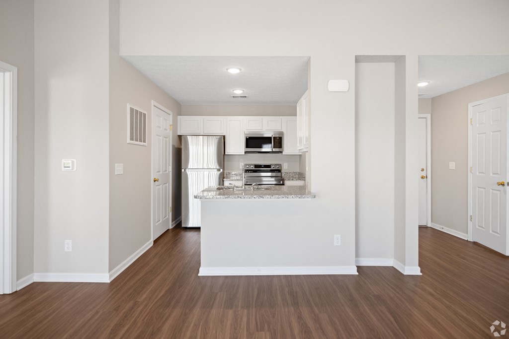 an empty living room and kitchen with white walls and wood floors