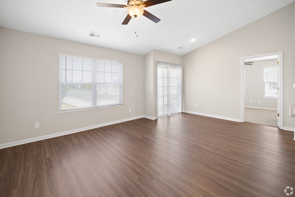 an empty living room with wood floors and a ceiling fan