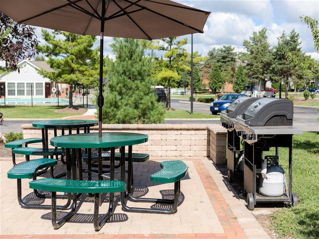 a patio with tables and chairs and a grill