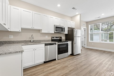 A kitchen with white cabinets and a granite countertop.