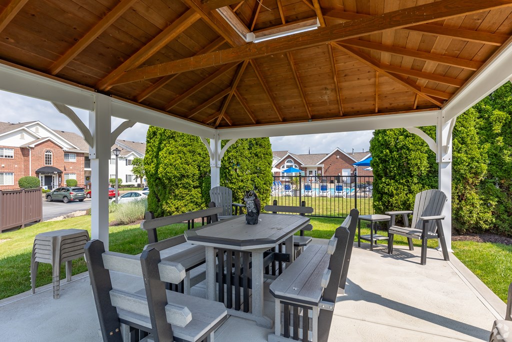 A wooden table and chairs are set up under a wooden roof.
