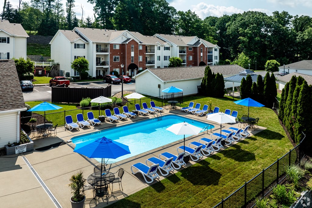 A swimming pool surrounded by lawn chairs and umbrellas.