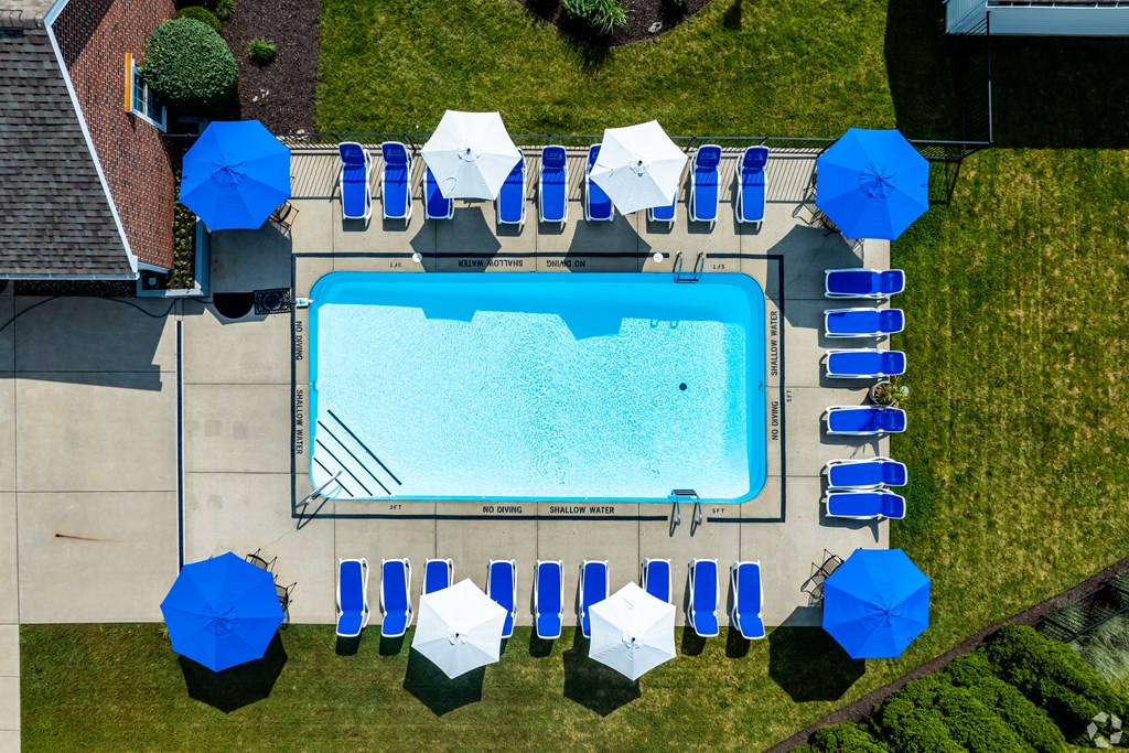 An aerial view of a swimming pool surrounded by blue and white umbrellas.