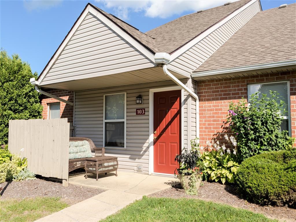 the front porch of a house with a red door