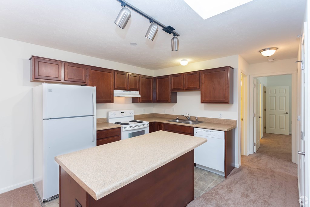 A kitchen with brown cabinets and a white fridge.