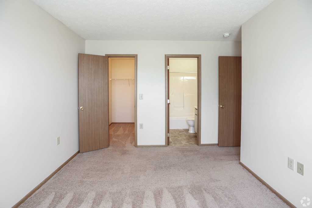 A room with a carpeted floor and two doors.