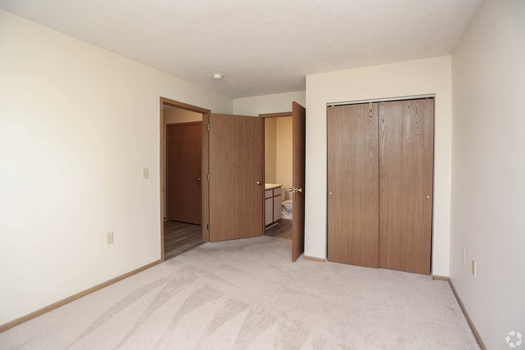 A room with a carpeted floor and two wooden doors.