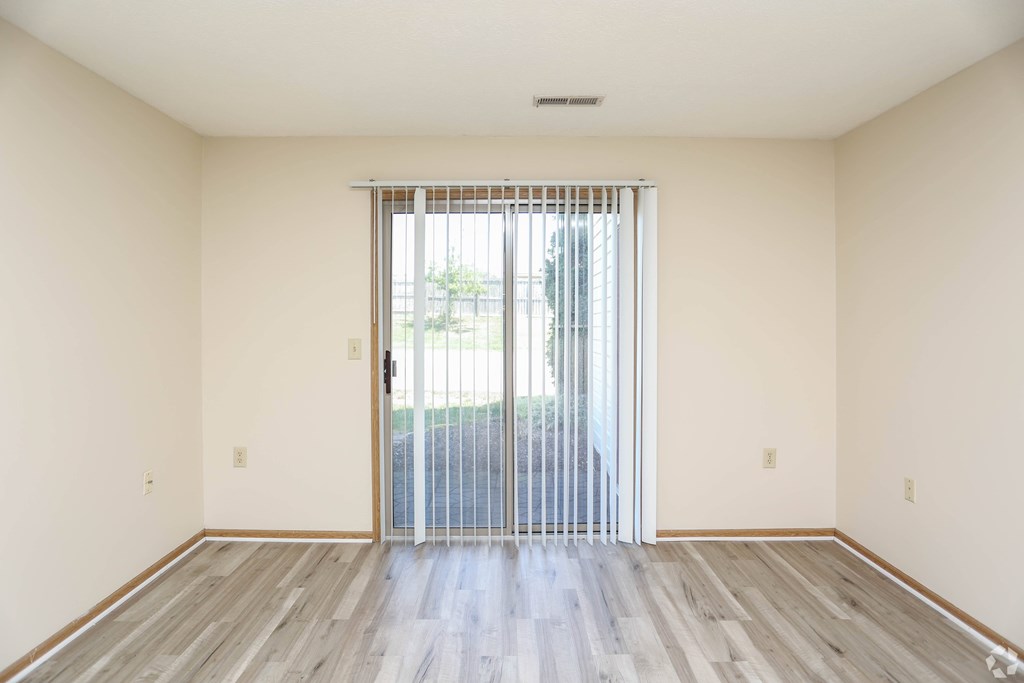A room with a sliding glass door and wooden flooring.