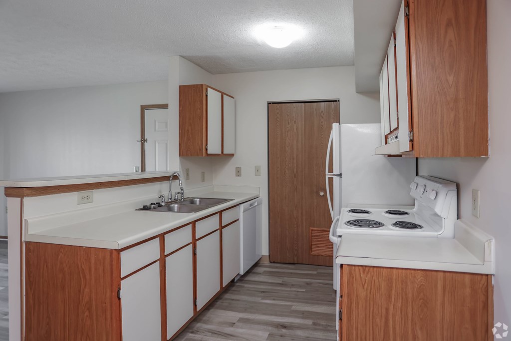A kitchen with white appliances and wooden cabinets.