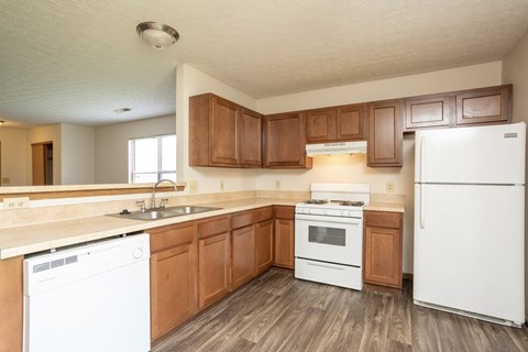 A kitchen with white appliances and wooden cabinets.
