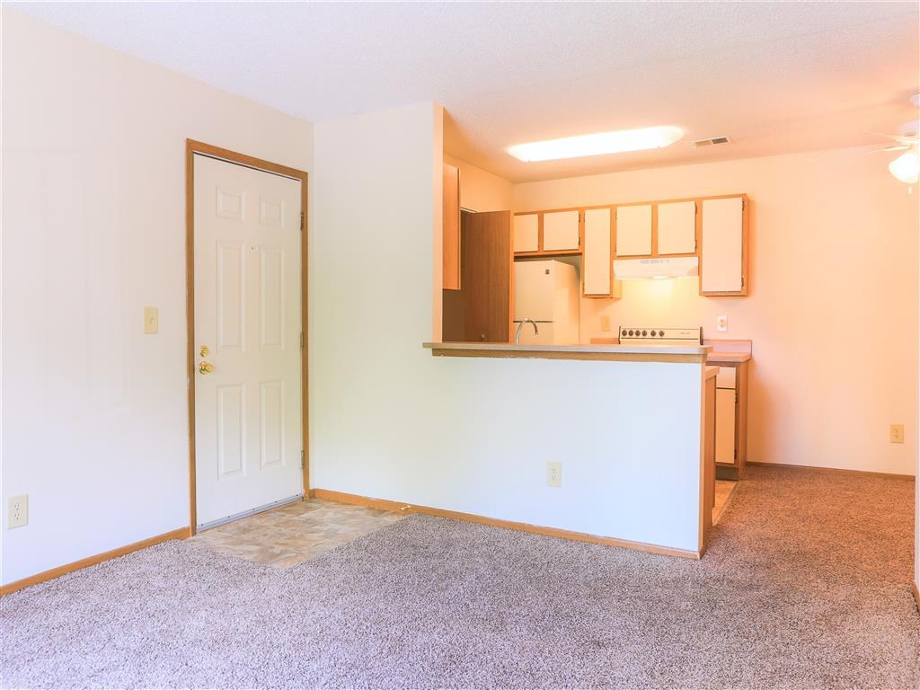 an empty room with a kitchen and a door