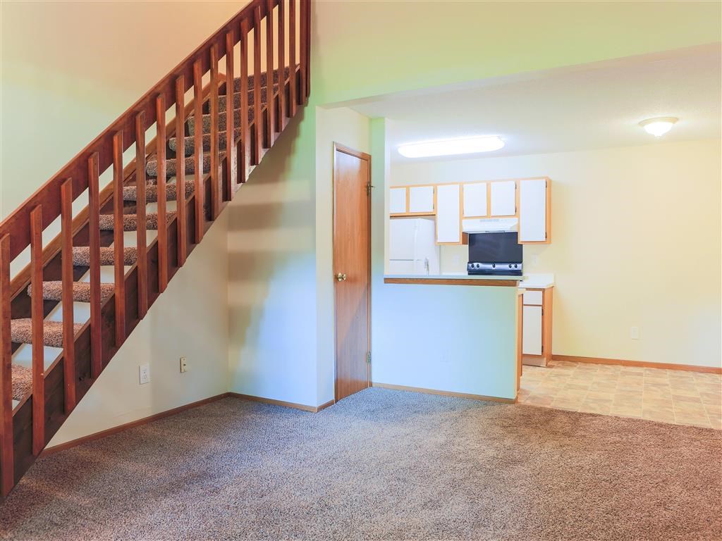 a living room with a staircase and a kitchen