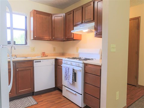A kitchen with brown cabinets and a white stove top oven.