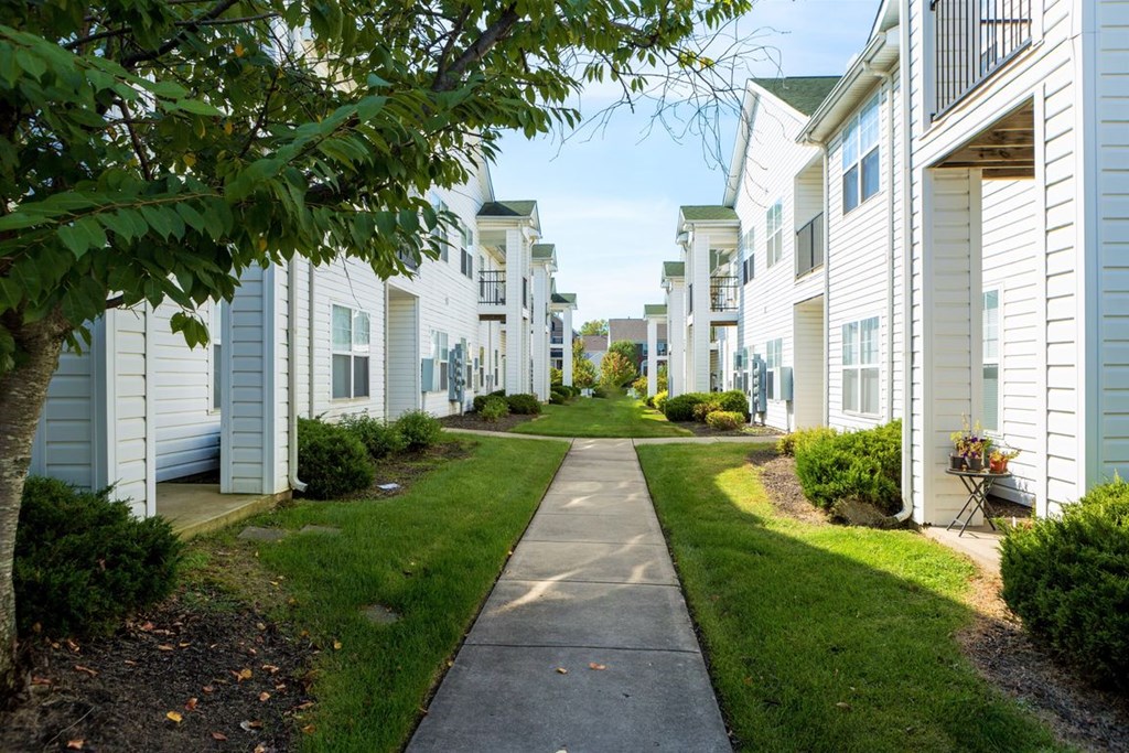 a sidewalk in front of a row of white houses