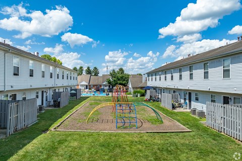 A playground with a swing set in the middle of a grassy area at River Valley Apartments in Lancaster, OH.