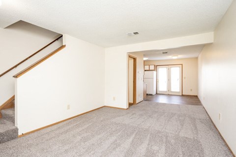 A spacious living room with a staircase on the left side.