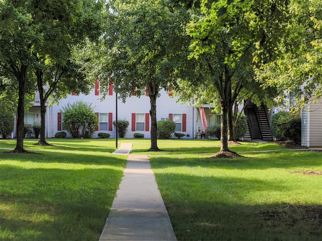 a sidewalk in front of a white house with trees
