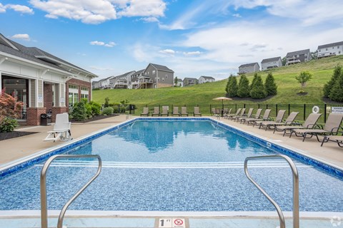 A swimming pool with a metal ladder and a red and white sign on the ground.