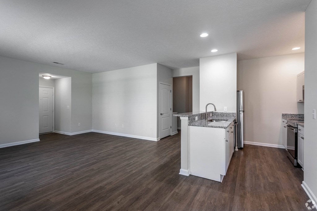 an empty kitchen and living room with white walls and wood flooring