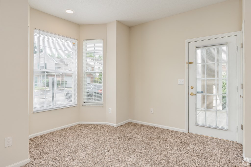 A room with a carpeted floor and a door with a window on the other side.