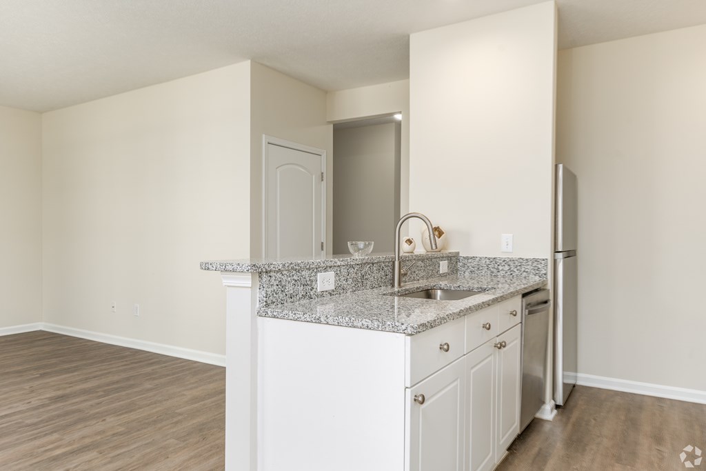 A kitchen with white cabinets and a granite countertop.