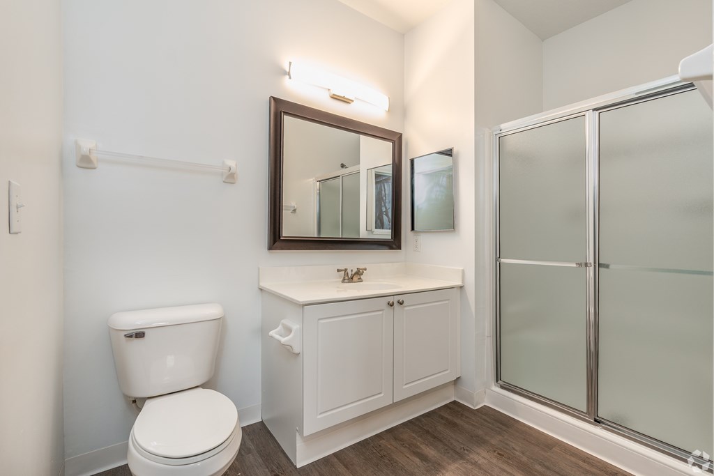 A white toilet sits next to a white cabinet with a mirror above it.