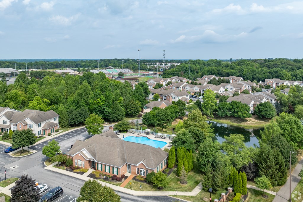 A bird's eye view of a residential area with a swimming pool and a road.