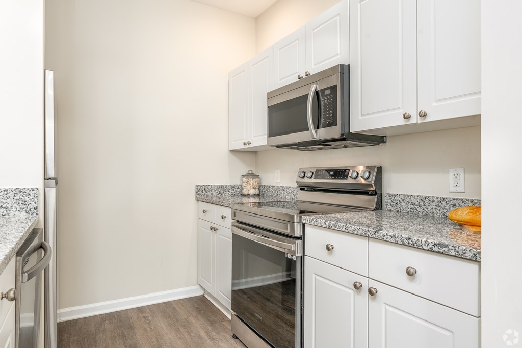 A kitchen with a granite countertop and white cabinets.