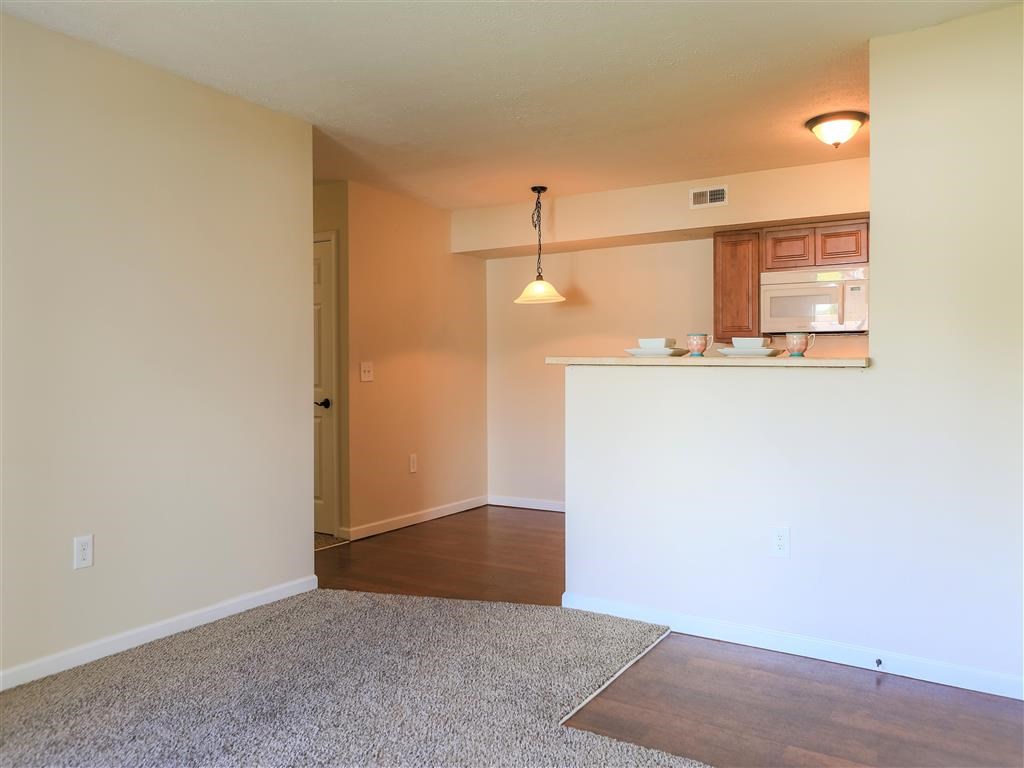 an empty living room with a kitchen and a microwave