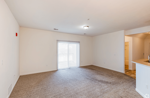 A large, empty room with a carpeted floor and a sliding glass door.
