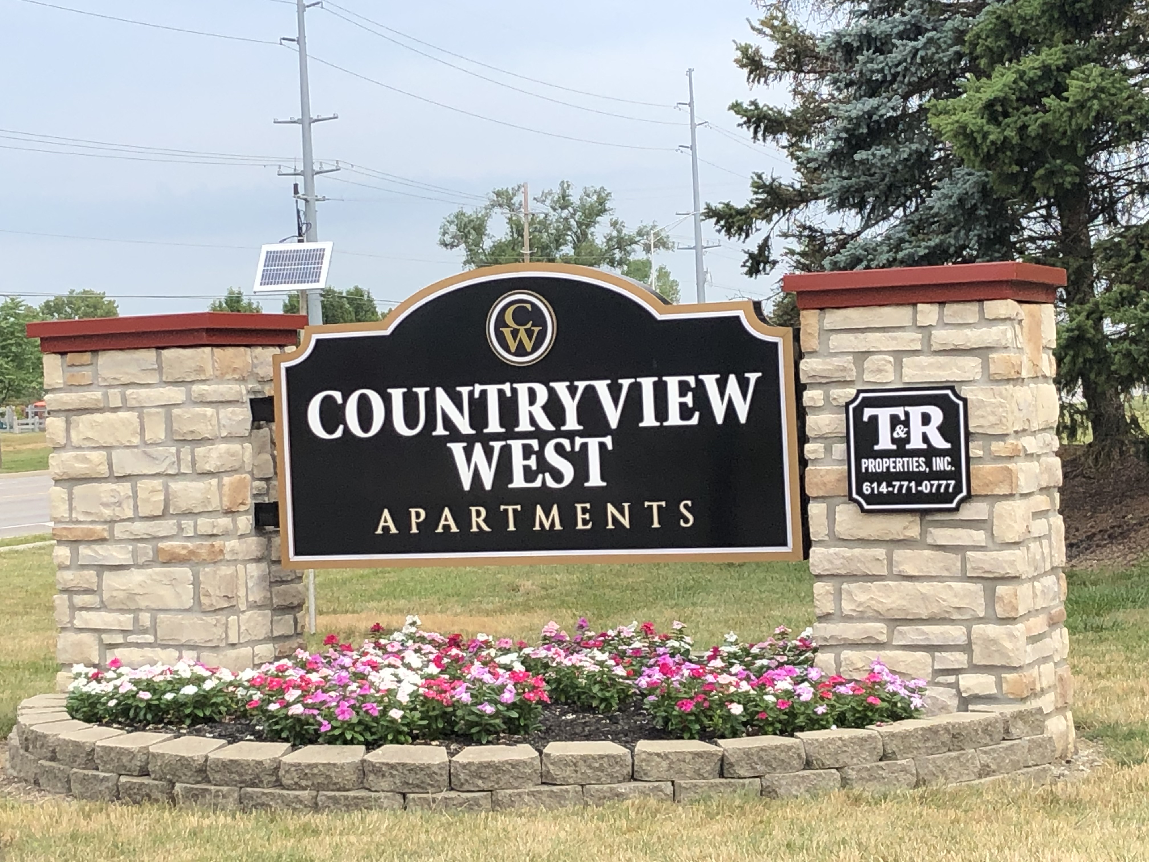 the sign for the countryview west apartments in front of a stone wall and flowers