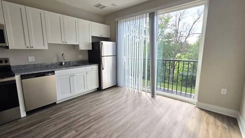 A kitchen with white cabinets and a black fridge.