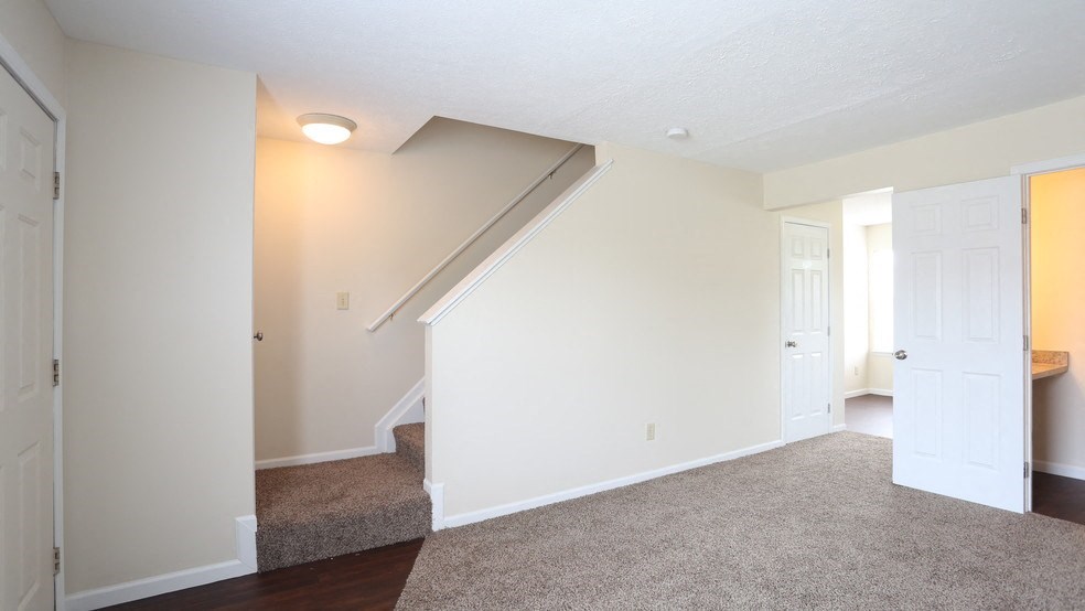 an empty living room with white walls and a staircase