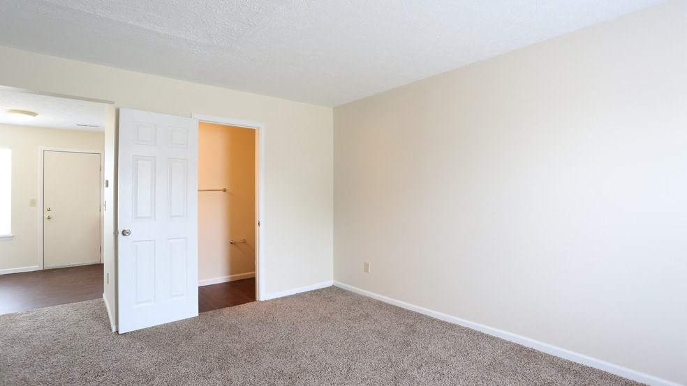 an empty living room with a white door and carpet